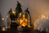 Glass cloche with a wooden house inside and golden lights. Christmas decoration at home. Festive decor at hotel or apartment for holiday season.