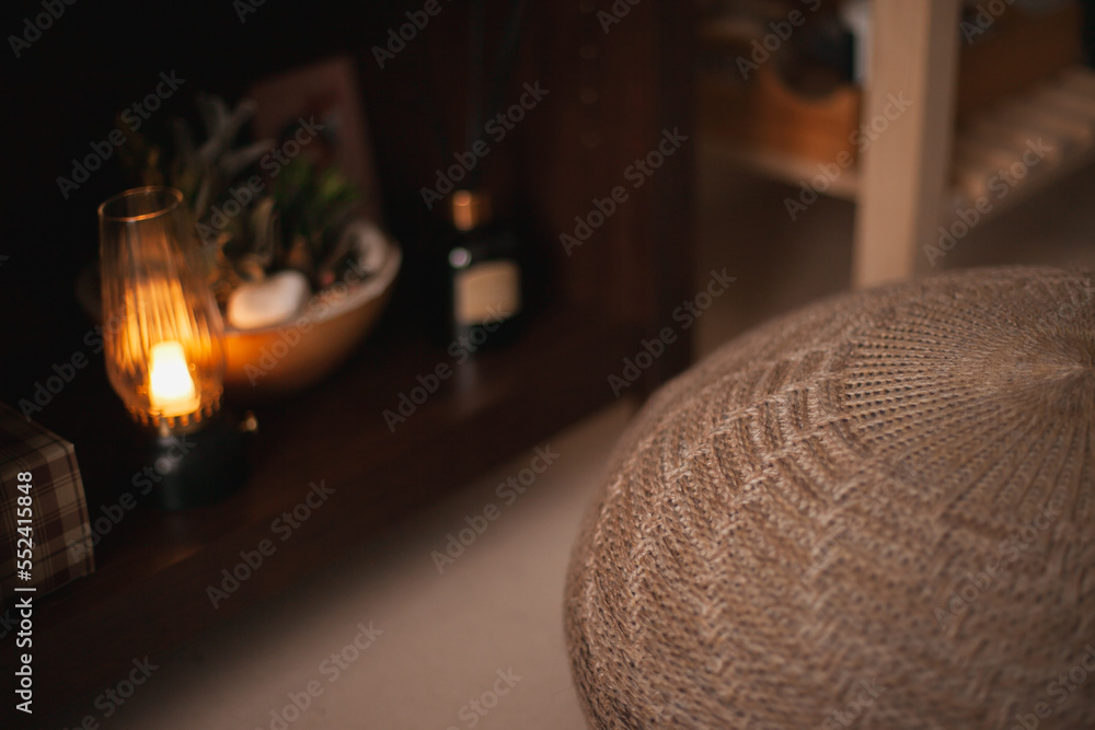 Cozy home decor with soft puff chair cushion and soft candle light. Apartment living. Interior design for cosy living. Cozy home decor with soft puff chair cushion and soft candle light. Apartment living. Interior design for cosy living.