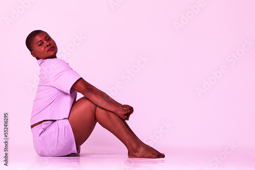 Taking Break. Overjoyed millennial plus-size black woman wearing white t-shirt and shorts, having fun moving and listening to music, relaxing isolated over white studio background