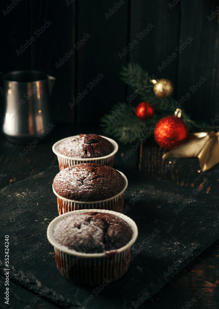 Chocolate muffins with powdered sugar on top on a black background. Christmas decoration . Still life close up. Food photo.