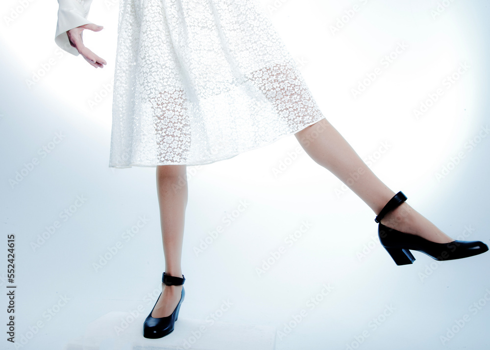 legs of a woman dancing, leaning, floating in a white dress with black heels legs of a woman dancing, leaning, floating in a white dress with black heels