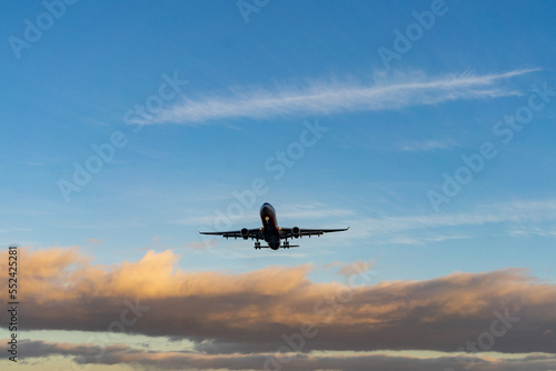 The silhouette of a passenger plane coming in for landing against the backdrop of the sunset sky. © fifg