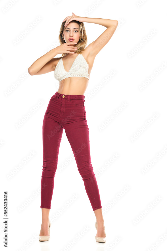 a young woman in burgundy jeans and top, and high heels shoes posing on a white background a young woman in burgundy jeans and top, and high heels shoes posing on a white background