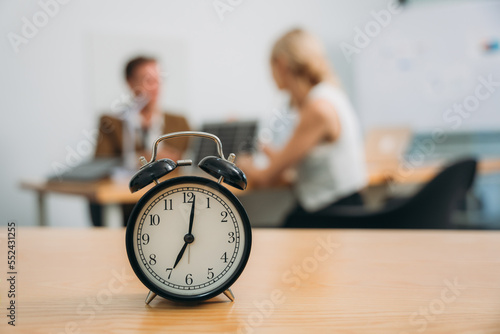 Workplace with alarm clock in modern style on background business meeting