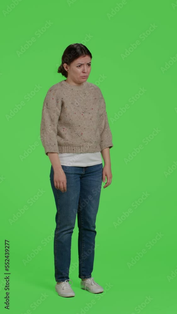 Vertical video: Side view of sad adult acting discouraged posing over isolated greenscreen backdrop, being disappointed and depressed. Young upset adult standing over full body studio background.