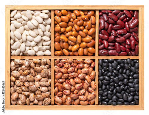 Variety of dried common beans, pulse assortment in a wooden box. White navy, Dutch brown, kidney, pinto, cranberry and black turtle beans. Phaseolus vulgaris seeds, in a wooden container, from above.