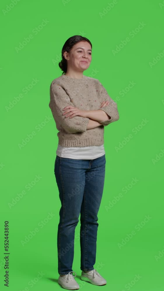 Vertical video: Side view of cheerful person standing on full body greenscreen with arms crossed, looking at camera. Young woman acting optimistic in studio, standing over isolated green screen Vertical video: Side view of cheerful person standing on full body greenscreen with arms crossed, looking at camera. Young woman acting optimistic in studio, standing over isolated green screen
