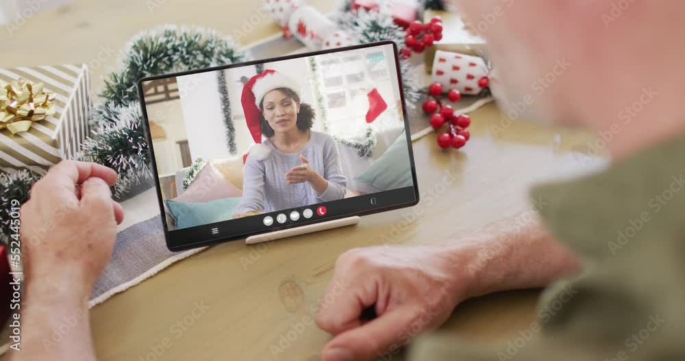 Caucasian man with christmas decorations having tablet video call with biracial woman