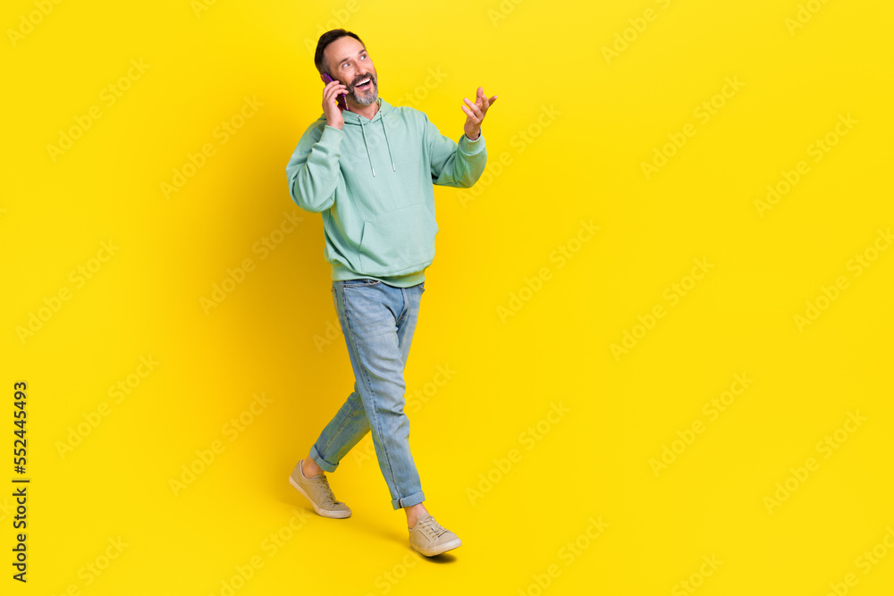 Full length photo of satisfied man walking street going looking empty space speaking friends 4g speed isolated on yellow color background Full length photo of satisfied man walking street going looking empty space speaking friends 4g speed isolated on yellow color background
