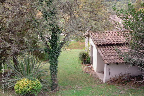 Pequeña casa del pueblo catalán en medio del monte con un precioso jardín verde con árboles con enredaderas que lo rodean. photo