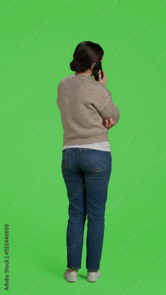 Vertical video: Back view of person talking on remote mobile phone call, using smartphone line to chat over full body greenscreen. Young happy woman using telephone to talk to people in studio Vertical video: Back view of person talking on remote mobile phone call, using smartphone line to chat over full body greenscreen. Young happy woman using telephone to talk to people in studio