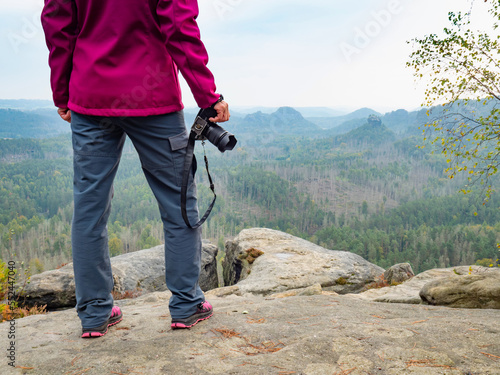 Woman photographer on cliff. Nature photographer hand holds mirror camera