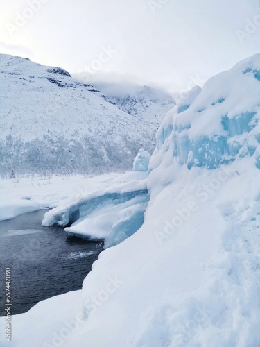 Northern landscape with frozen fountain in shape of blue ice hill in Khibiny mountains. Winter natural phenomenon. Kirovsk, Kola Peninsula, Murmansk region.