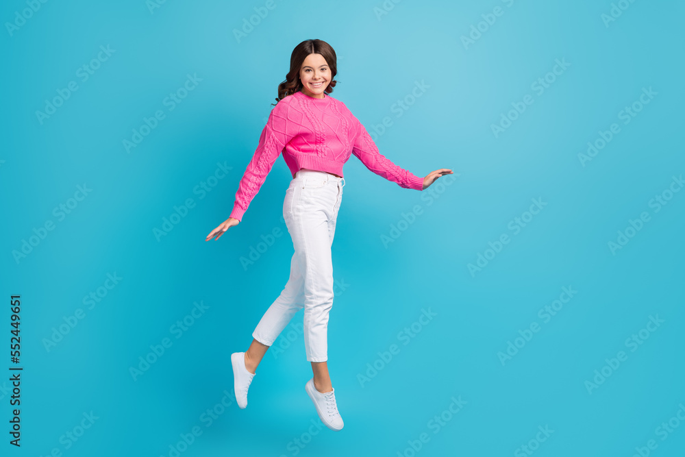 Obraz premium Full length photo of cute pretty girl dressed knit pullover jumping high walking empty space isolated blue color background