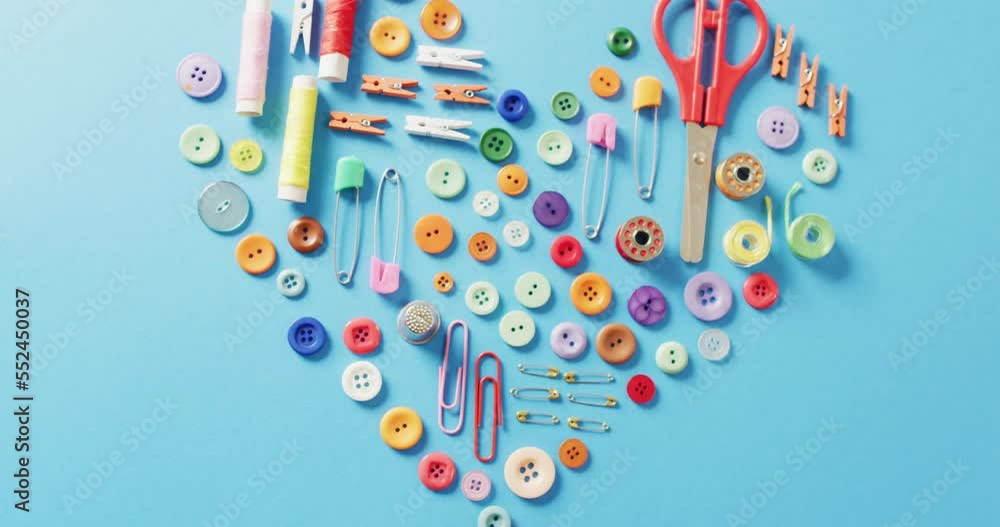 Video of scissors, buttons, pins, clips, pegs and cotton reels in a heart shape on blue background Video of scissors, buttons, pins, clips, pegs and cotton reels in a heart shape on blue background