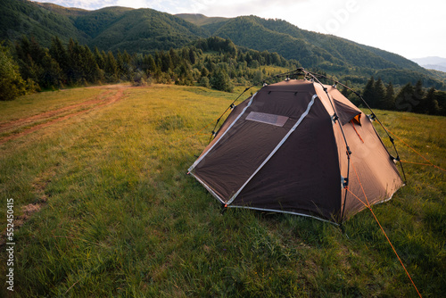 Brown tent with quick installation system. Standing in the rays of the sun on the top of the mountain. Summer, rest, camping. Copy space.