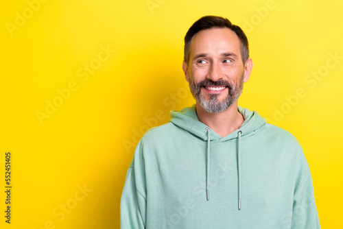 Portrait of mature age man brown hair grey old bristle smiling looking good deal empty space cheap electronics isolated on yellow color background