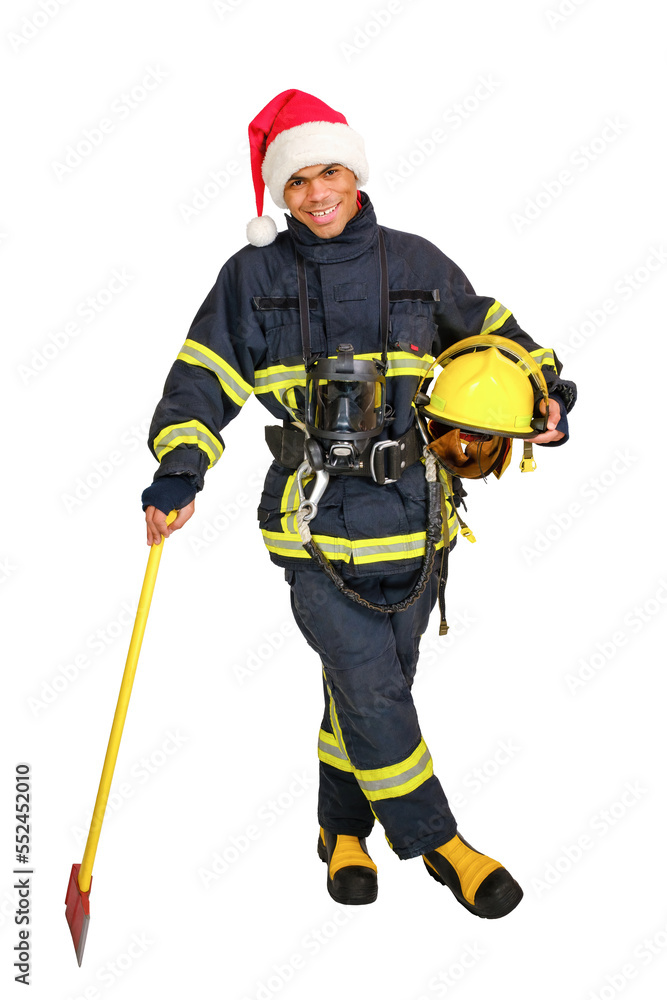 Full body young African-American fireman in fire-proof uniform and red santa hat, holds axe and yellow hard hat in hands over white background isolated. Full body young African-American fireman in fire-proof uniform and red santa hat, holds axe and yellow hard hat in hands over white background isolated.