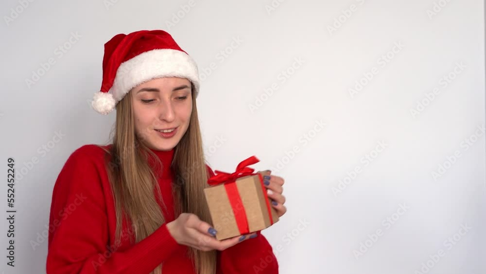 A girl dressed as Santa receives a Christmas present in a box with a red ribbon. New Year holidays. A girl dressed as Santa receives a Christmas present in a box with a red ribbon. New Year holidays.