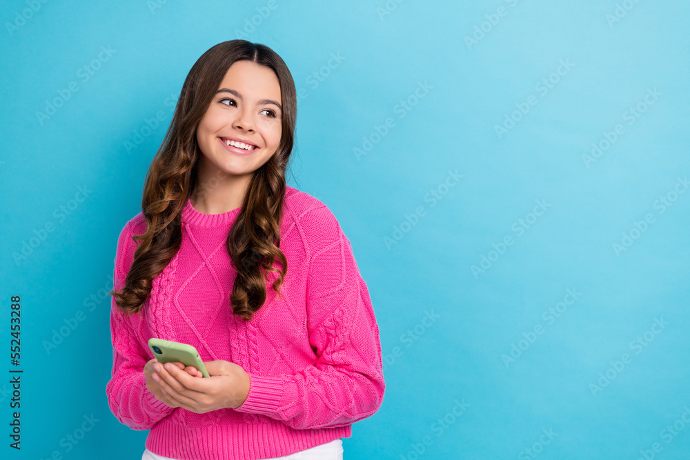 Fototapeta premium Photo of young dreamy lovely schoolgirl teen aged hold apple iphone look curious empty space useful convenient app isolated on blue color background