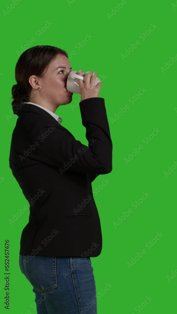 Vertical video: Profile of office worker holding cup of coffee and drinking refreshment in studio, standing over isolated greenscreen. Corporate manager in suit serving caffeine beverage or drink Vertical video: Profile of office worker holding cup of coffee and drinking refreshment in studio, standing over isolated greenscreen. Corporate manager in suit serving caffeine beverage or drink