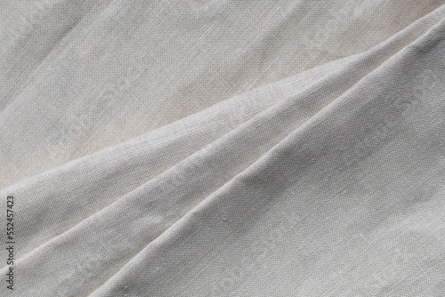 Textured folds of linen fabric in natural beige color. Textile background, top view, copy space