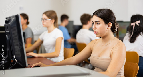 Focused Latin female teenager solving tasks of computer science in the auditory.