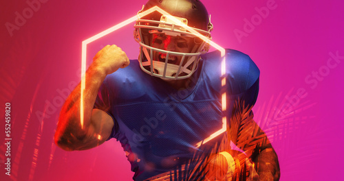 Cheerful american football player gesturing while standing by illuminated hexagon and plants