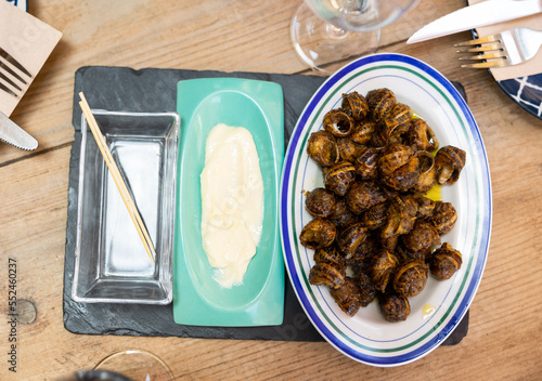 Plate of Caracoles a la llauna, delicacy of Catalan cuisine of land snails cooked in shells on grill accompanied by aioli sauce. Authentic cuisine photo