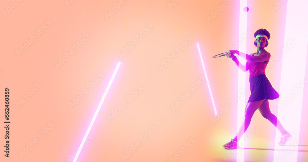 Full length of biracial female player playing tennis by illuminated lines on peach background Full length of biracial female player playing tennis by illuminated lines on peach background