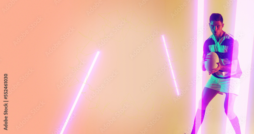 Caucasian male player holding rugby and standing by illuminated lines over peach background Caucasian male player holding rugby and standing by illuminated lines over peach background