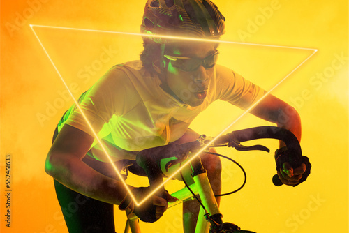 Triangle neon over determined african american cyclist riding bicycle against yellow background