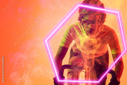 Hexagon neon over determined african american cyclist riding bicycle against orange background
