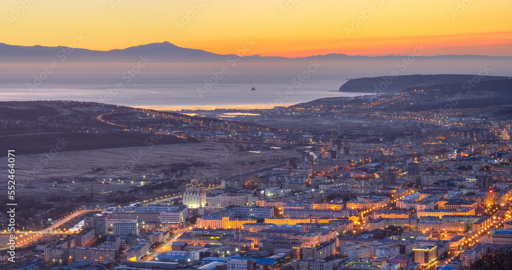 Beautiful morning aerial view of the city. Top view of the cathedral, buildings and streets at dawn. In the distance the sea bay and mountains. City of Magadan, Magadan region, Far East of Russia.
