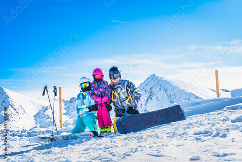 Family on ski and snowboard, winter holidays, with beautiful snow capped mountains in the background in Andorra, El Tarter, Pyrenees Mountains