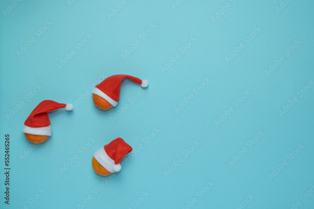 Christmas, New Year blue stylish flat frame with tangerines in santa hats. Winter holiday composition. View from above. copy space Christmas, New Year blue stylish flat frame with tangerines in santa hats. Winter holiday composition. View from above. copy space