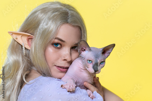 Canvas-taulu Portrait of cosplay elf young woman holding Sphinx cat near cheek