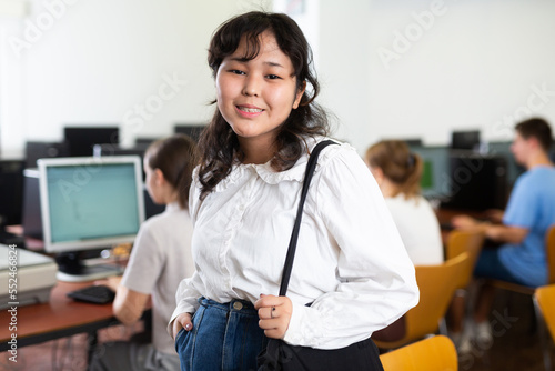 Portrait of smiling asian teen schoolgirl in the computer class of the school