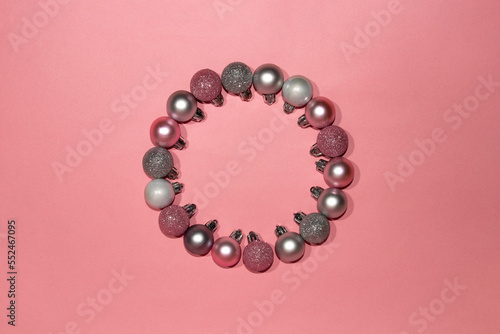 Pink and silver ornaments wreath on pink background. Christmas concept. Flat lay top view circle frame.