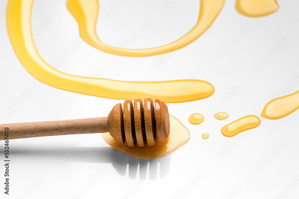 dipper for honey lies in liquid honey on a white background. dipper for honey lies in liquid honey on a white background.