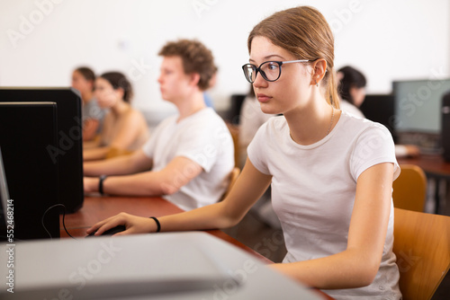Portrait of interested teen girl during lesson in computer room of school computer class © JackF