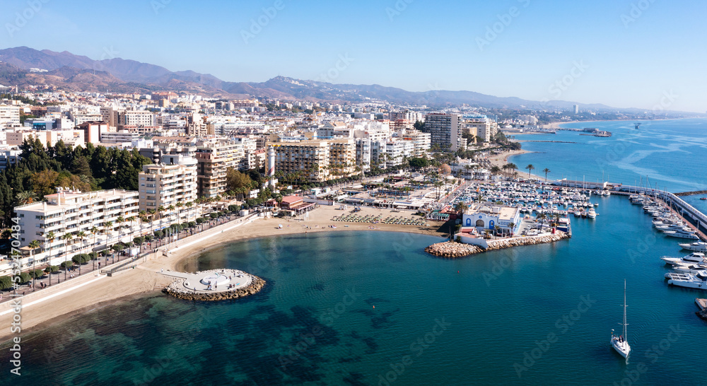 Scenic aerial view of Spanish tourist town of Marbella on Mediterranean coast with harbour on sunny autumn day, province of Malaga