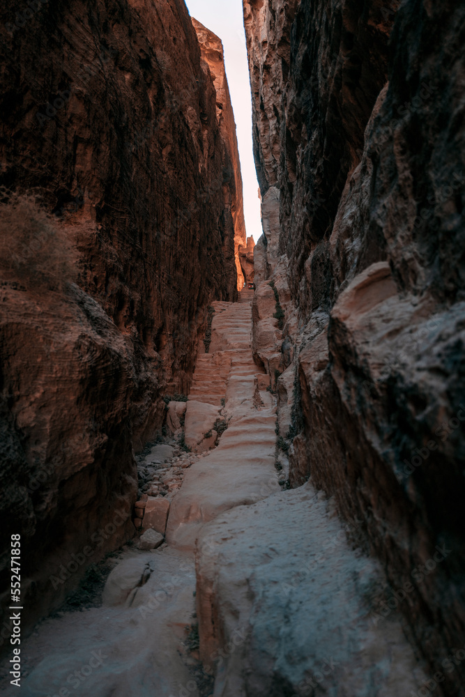 ancient steps pass through a sandstone alleyway in the Middle East where bedouin tribes would walk to the mountain. The photo is in Little Petra, Jordan ancient steps pass through a sandstone alleyway in the Middle East where bedouin tribes would walk to the mountain. The photo is in Little Petra, Jordan