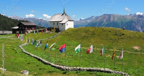 Bettmeralp, Switzerland - July 16, 2022: A church of Bettmeralp with waving swiss cantonal flags, located above the Rhone Valley in Upper Valais in Switzerland photo