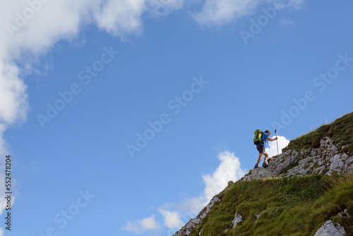 Athletic mountaineer ascending, profile against blue sky, copyspace