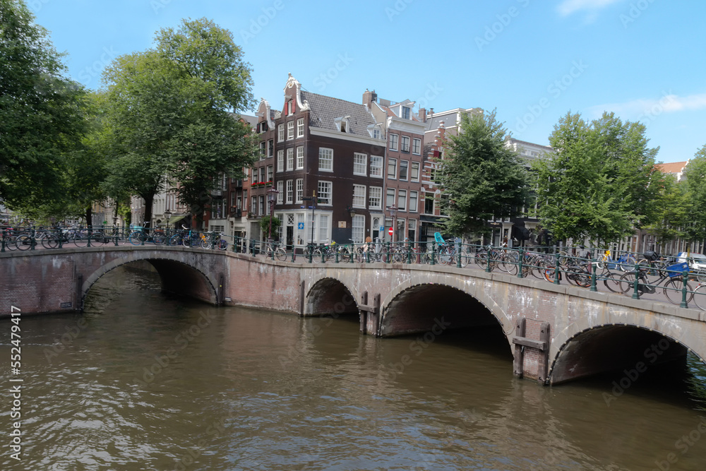 Bicycles on the bridge and the streets of amsterdam. View of the canal and arches of the bridge