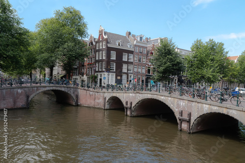 Bicycles on the bridge and the streets of amsterdam. View of the canal and arches of the bridge