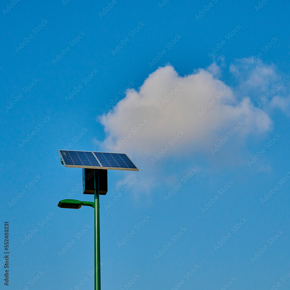 solar powered park lamp against bright blue sky with puffy white cloud solar powered park lamp against bright blue sky with puffy white cloud