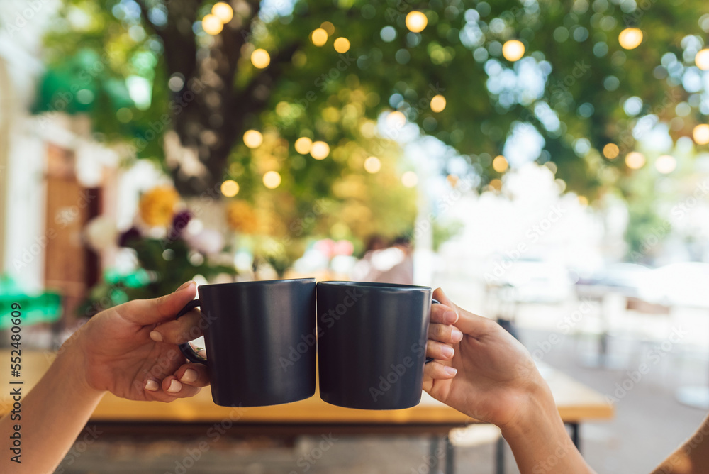 Closeup image of a people clinking coffee cups together in cafe Closeup image of a people clinking coffee cups together in cafe
