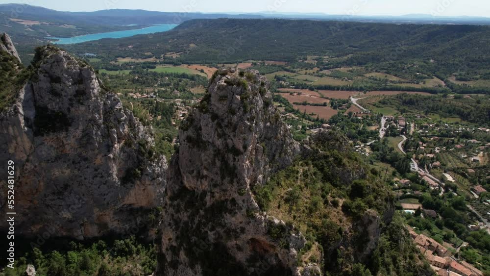 Discovering Moustiers-Sainte-Marie village along mountains aerial shot sunny day France
